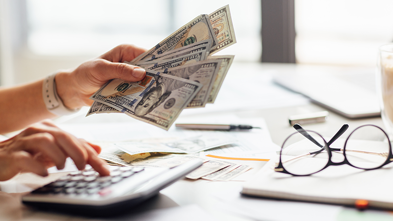 Person using a calculator while handling cash.