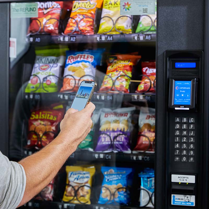 Customer uses mobile wallet at a cashless payment device on a stocked vending machine.