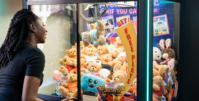 Woman plays a claw machine full of stuffed animals.