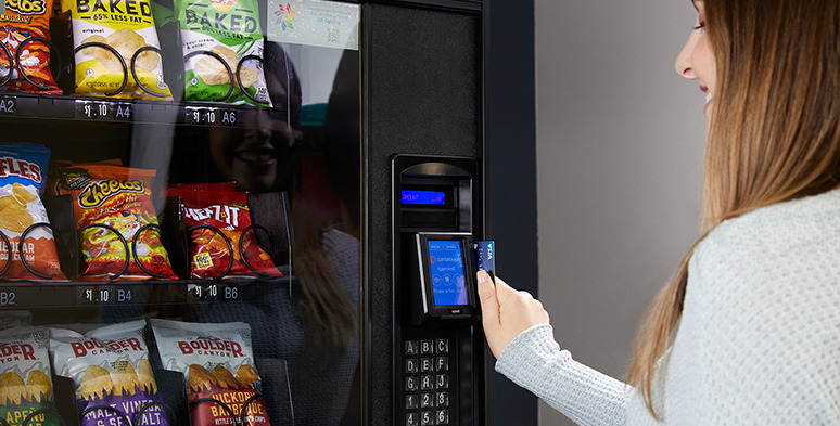 Woman swipes credit card at a vending machine card reader.