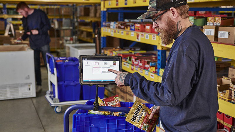 Warehouse worker picks a tote full of snacks for a route.